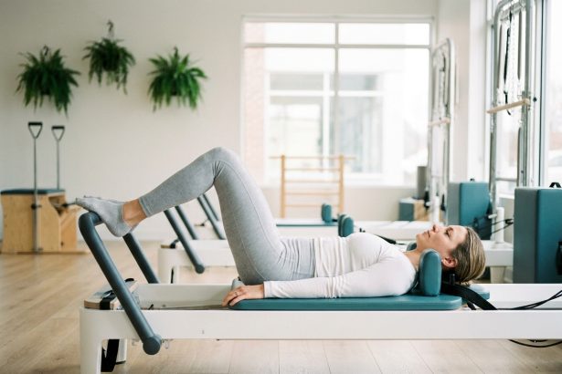 Femme pratiquant le pilates sur un reformer dans un studio moderne après une blessure sportive