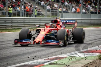 Monoplace de Formule 1 en plein virage sur un circuit moderne, avec les tribunes en arrière-plan floutées et la texture de l'asphalte visible au premier plan