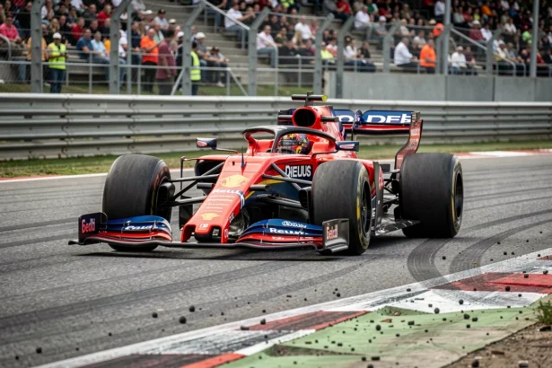 Monoplace de Formule 1 en plein virage sur un circuit moderne, avec les tribunes en arrière-plan floutées et la texture de l'asphalte visible au premier plan