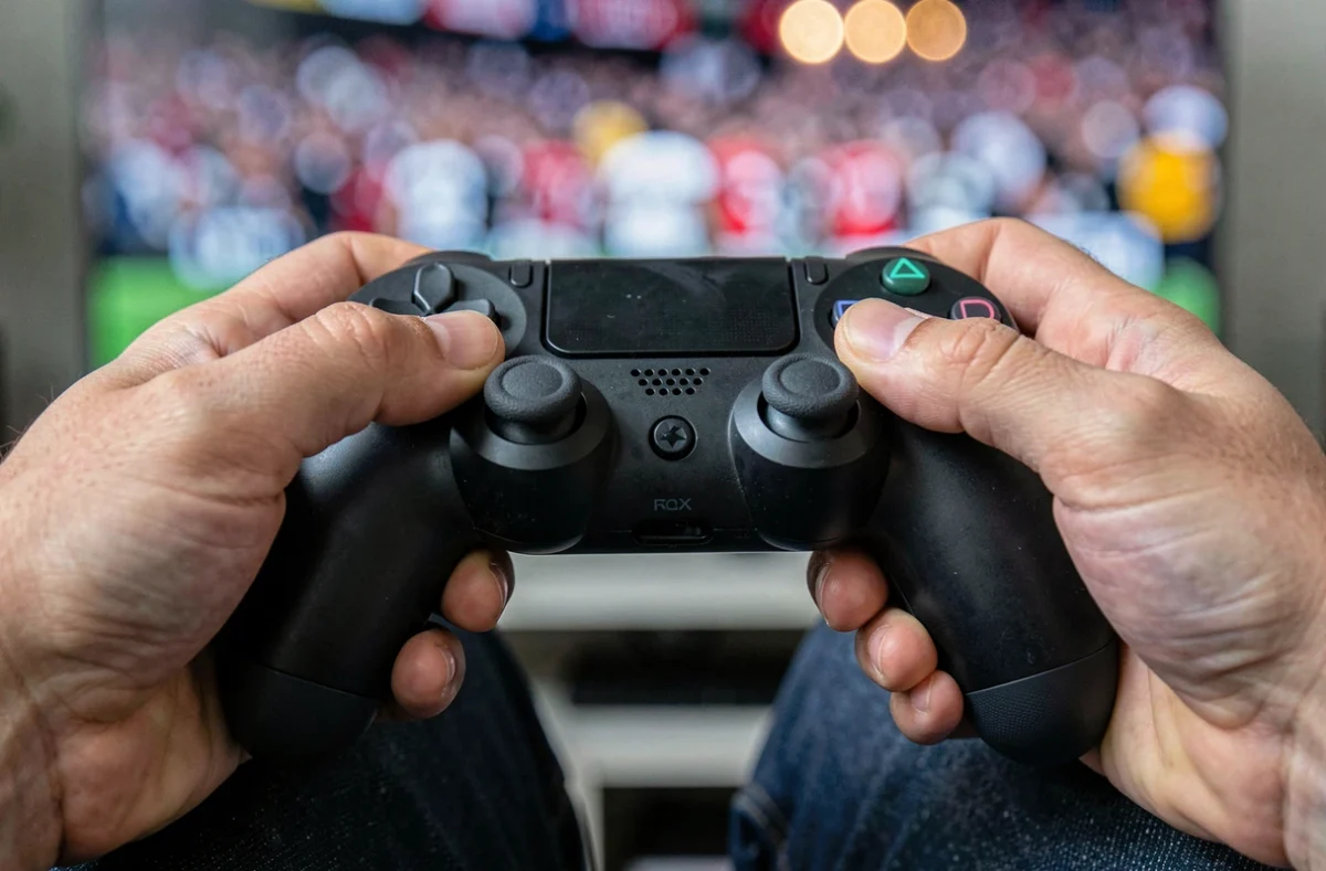 Gros plan de mains tenant une manette PlayStation lors d'une partie FC 25, symbolisant la maîtrise des gestes techniques 5 étoiles
